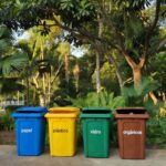 Lixeiras coloridas de reciclagem em praça de Ji-Paraná para descarte correto de lixo.