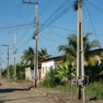 Postes de energia e hidrômetros em rua de Ji-Paraná representando serviços de luz e água