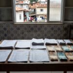Documentos financeiros e notas de real em mesa de casa brasileira sobre endividamento familiar
