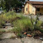 Calçada com mato e entulho em frente ao Colégio 21 de Abril